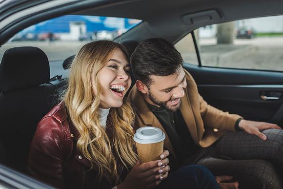 couple laughing and drinking coffee in back of car