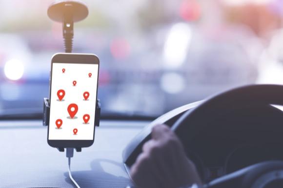 Phone with Map pins all over screen in phone holder in car while man drives